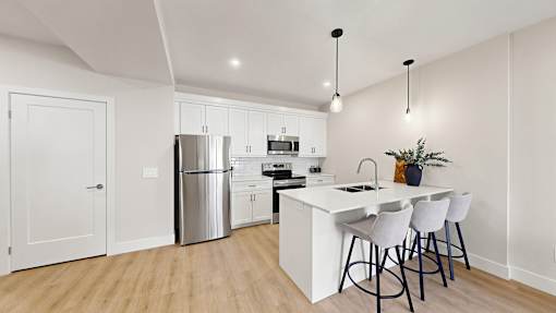 A modern kitchen with white cabinets and a white island.