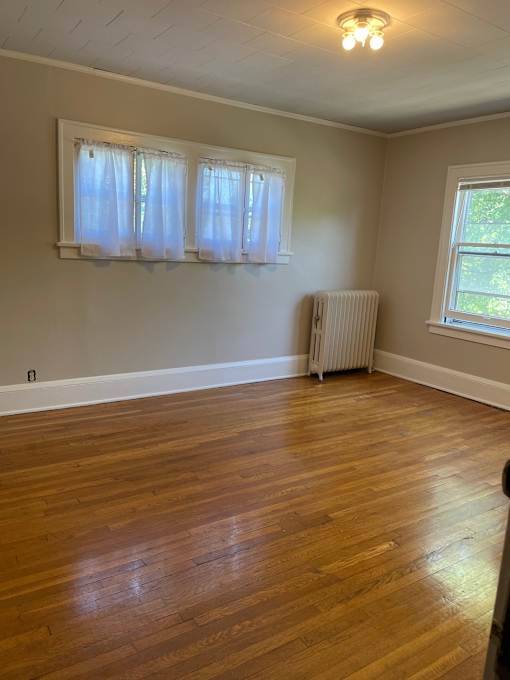 A room with wooden floors and a window with curtains.