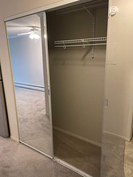 A large empty closet with a mirrored door.