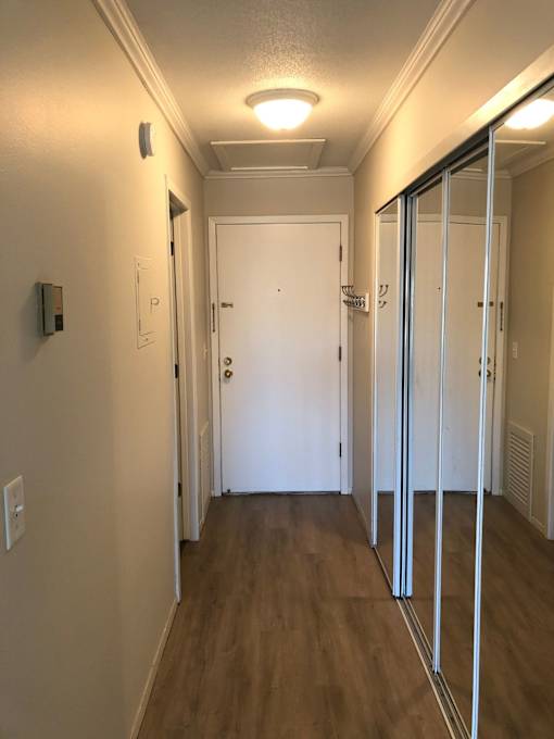 A hallway with a white door and a white wall.