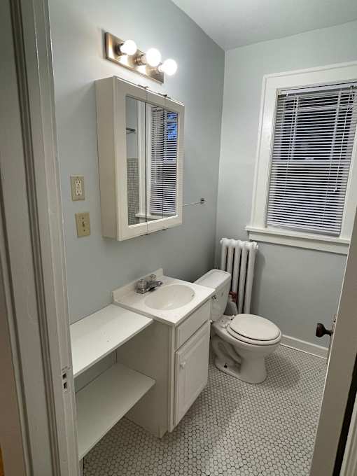 A white bathroom with a toilet, sink, and mirror.