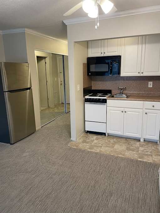 A kitchen with white cabinets and a stainless steel refrigerator.
