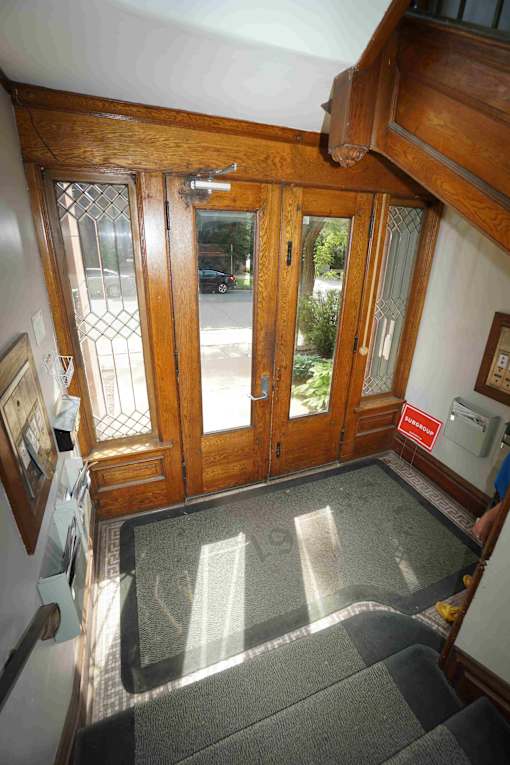 A wooden door with glass panels is flanked by two wooden posts.