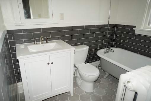 Updated bathroom with hexagon tiled floor, tiled walls, and updated fixtures, along with vintage clawfoot tub.