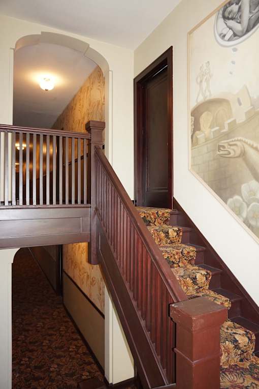 A staircase with a wooden handrail and a patterned carpet.