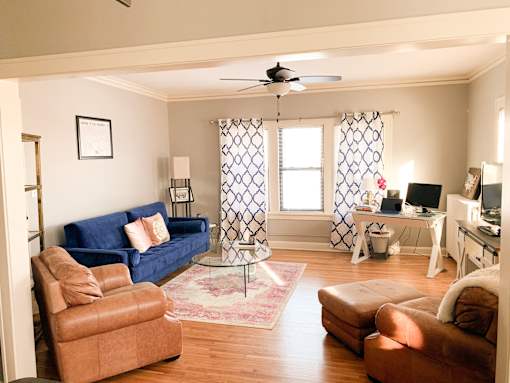 A living room with a blue couch and brown chairs.