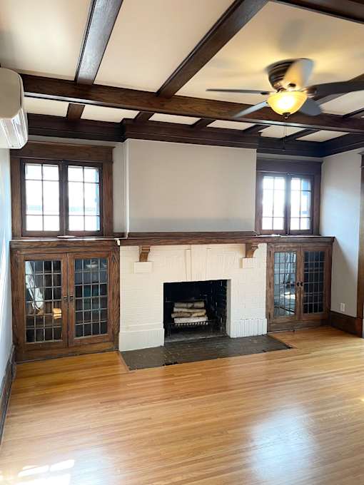 Elegant living room with coffered oak ceilings, brick fireplace, built-in oak buffet cabinets and hardwood floors.