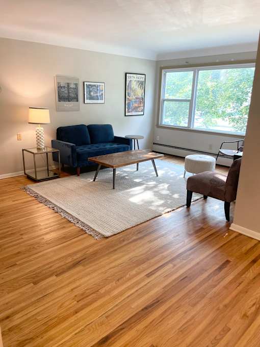 A living room with a blue couch and a white rug.