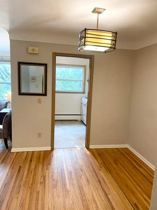 A room with a wooden floor and a doorway leading to a balcony.