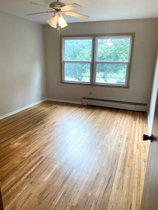 A room with wooden flooring and a ceiling fan.