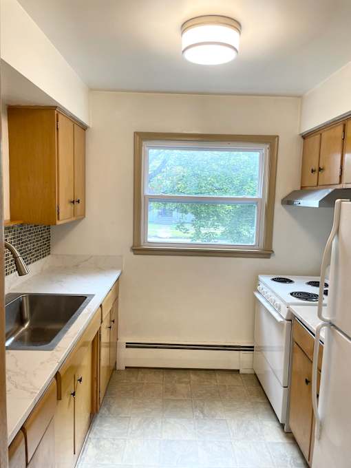 A kitchen with white appliances and wooden cabinets.