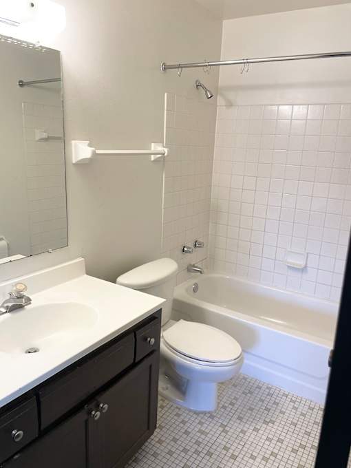 Comfortably sized bathroom with large vanity and mirror, and ceramic tiled floor and shower surround.