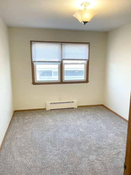 A room with a window and a heater on the floor.