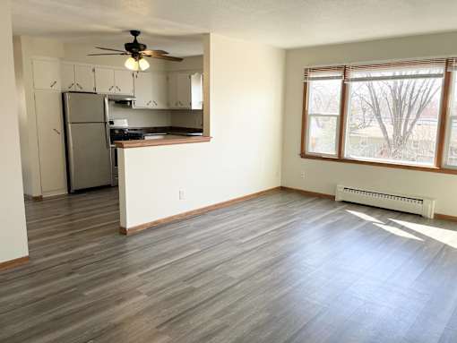 A kitchen with a refrigerator, cabinets, and a ceiling fan.
