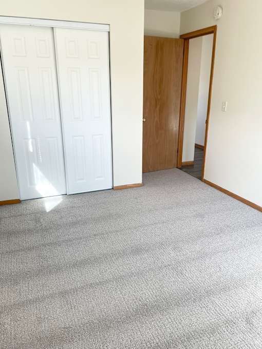 A room with a carpeted floor and a white door.