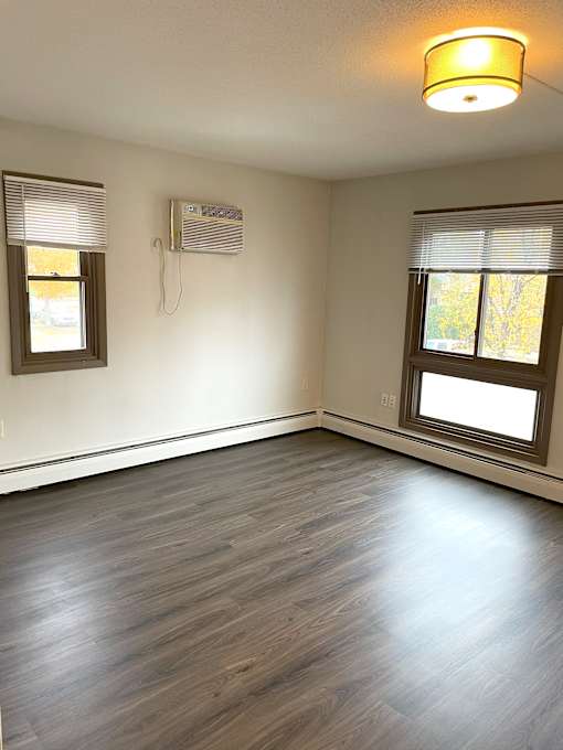A room with a window and a wall-mounted air conditioner unit.