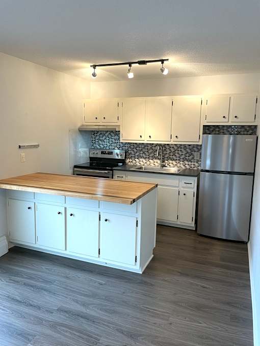 A kitchen with white cabinets and a wooden island.