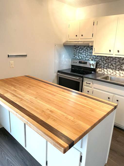 A kitchen with a wooden counter top and white cabinets.