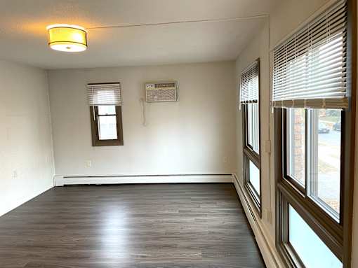 A room with wooden floors and a window with blinds.