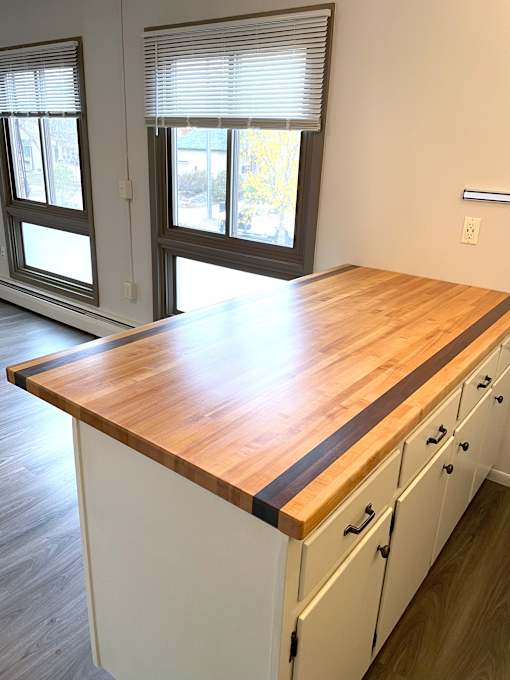 A kitchen with a wooden counter top and white cabinets.