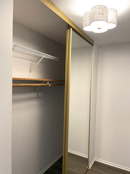 A white closet with a shelf and a light on.