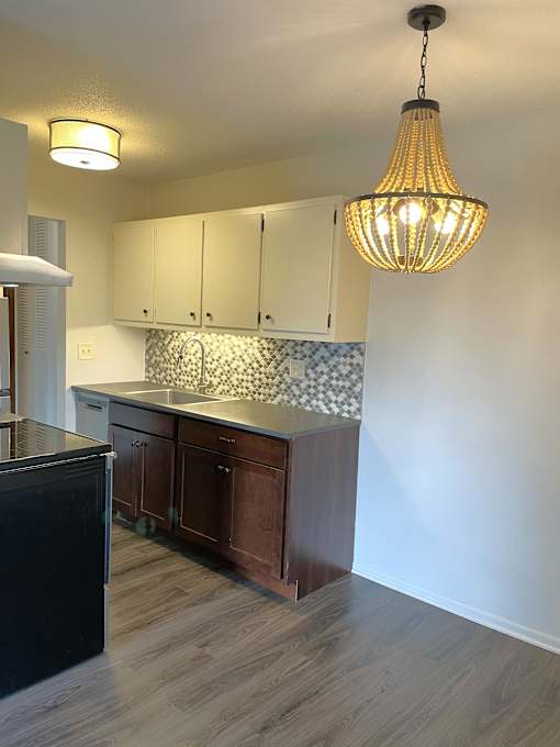 A kitchen with a black fridge and wooden cabinets.