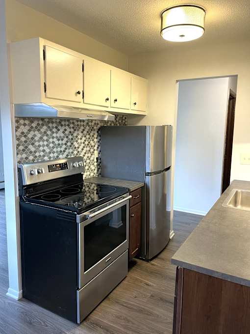 A kitchen with a black stove top oven and a stainless steel refrigerator.