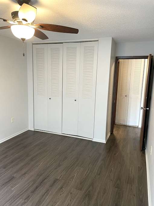 A room with a ceiling fan and three white doors.