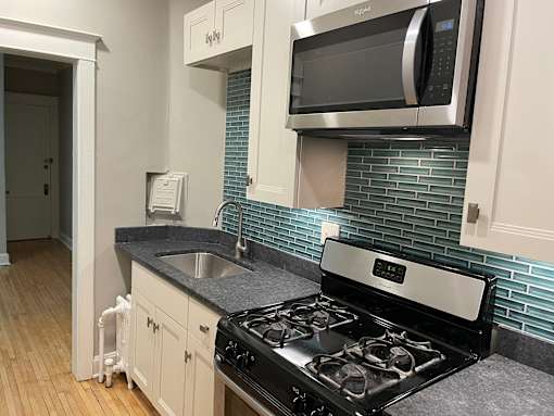 Custom kitchen cabinets, granite countertops, stainless steel appliances including microwave over stove.