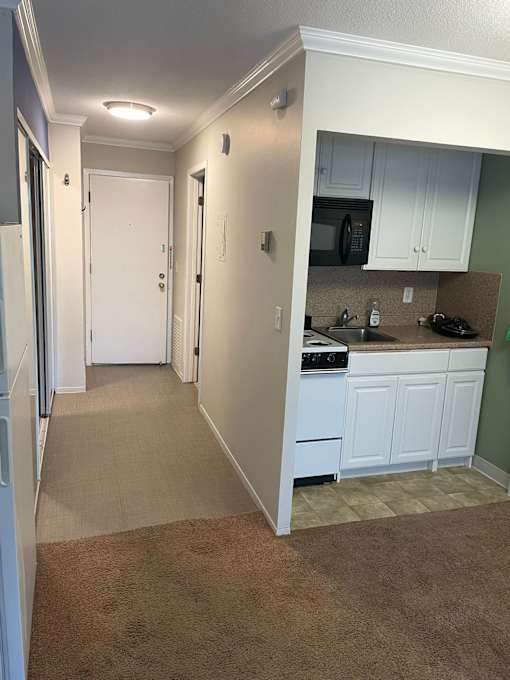 A kitchen with white cabinets and a white door.