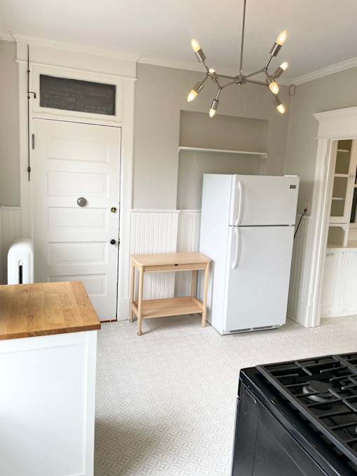 A kitchen with a white fridge and a wooden table.