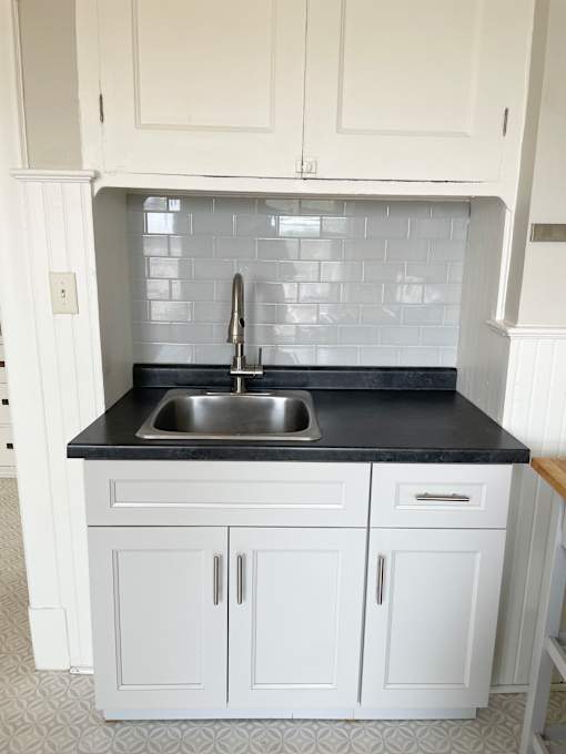 A kitchen with white cabinets and a black countertop.