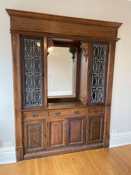A wooden cabinet with glass doors and drawers.