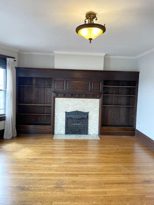 A fireplace with a white mantle and a wooden shelf above it.