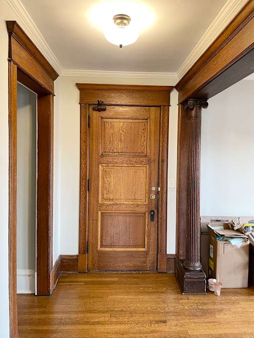 A room with a wooden door and a trash can.