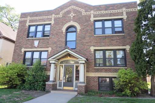 A red brick building with a large arched window and a doorway.