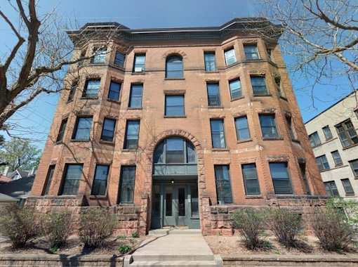 A red brick building with a large arched entrance and a stone wall.