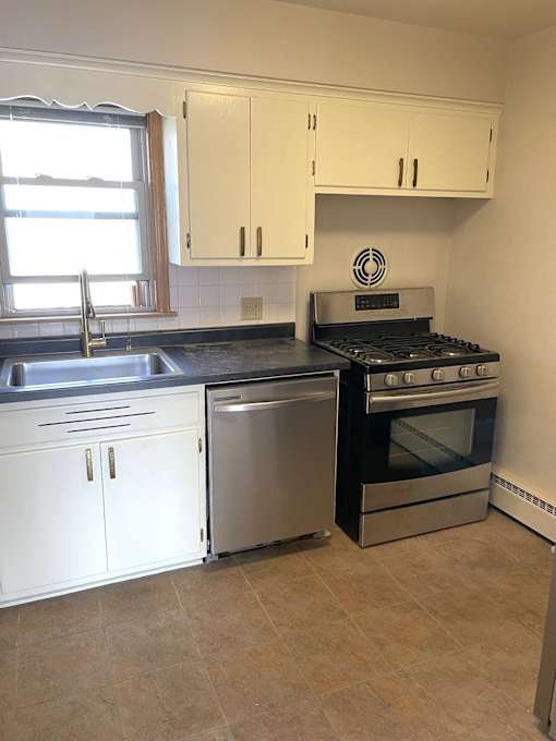 A kitchen with wooden floors and white cabinets.