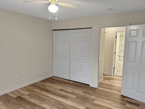 A room with a ceiling fan and a white door.