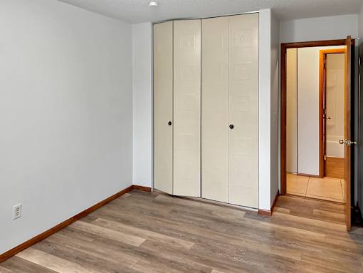 A room with a white wall and a brown floor with a white closet.