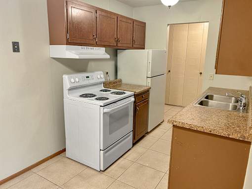 A kitchen with a white stove and a white refrigerator.