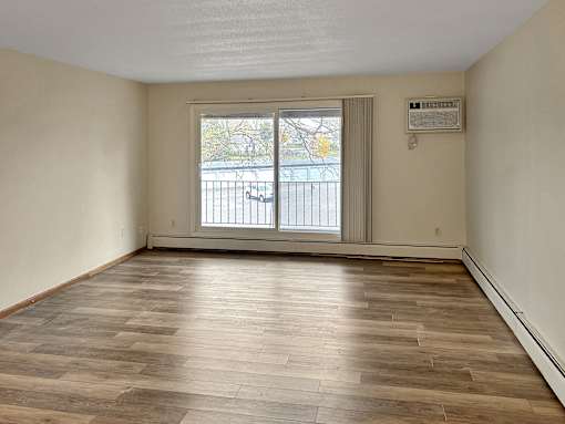 A room with wooden flooring and a window with blinds.