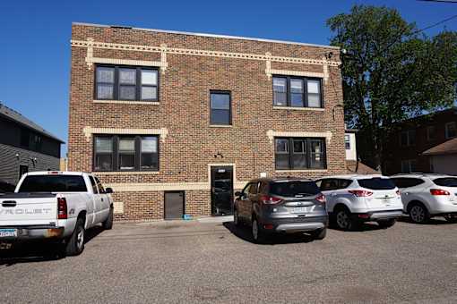 A white pickup truck is parked in front of a brick building.