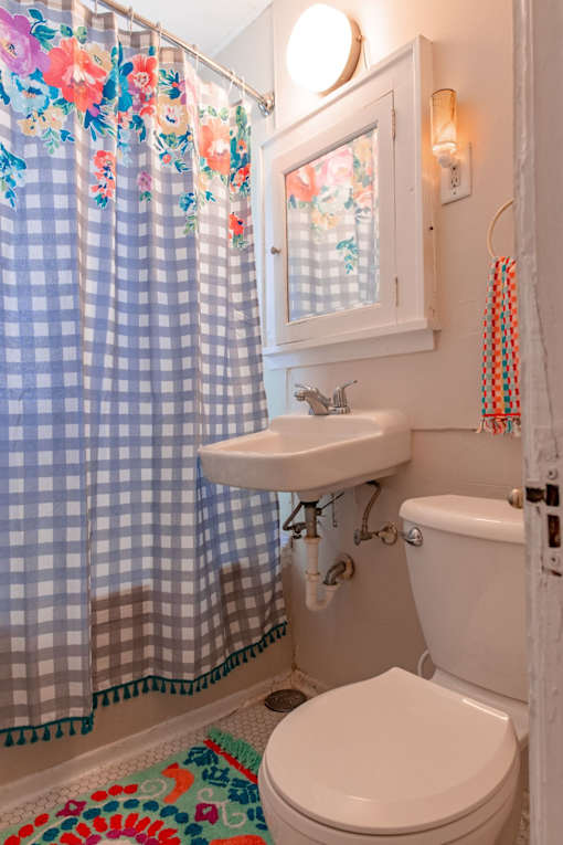 A bathroom with a toilet, sink, and shower curtain.