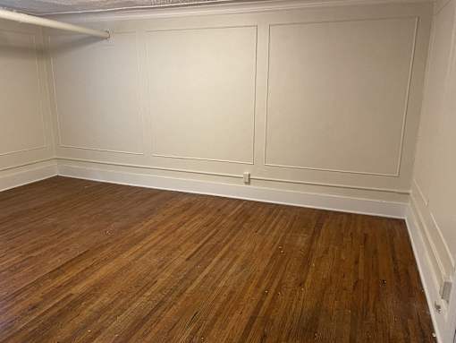 A room with wooden flooring and white walls.