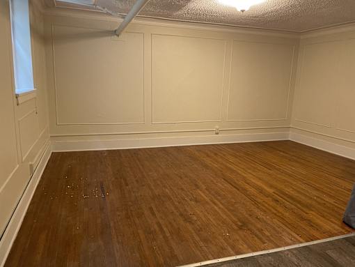 A room with wooden flooring and white walls.