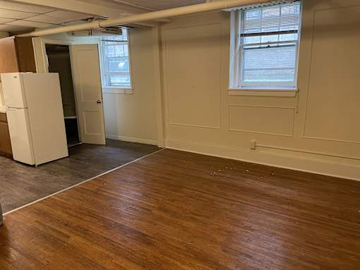 A room with wooden floors and a white refrigerator.