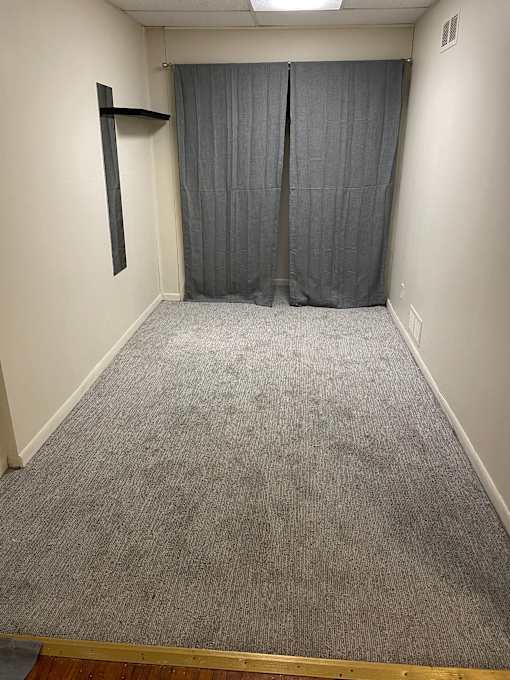 A room with a grey carpet and a grey curtain.