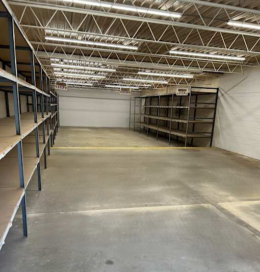 A large empty warehouse with metal shelving and a concrete floor.