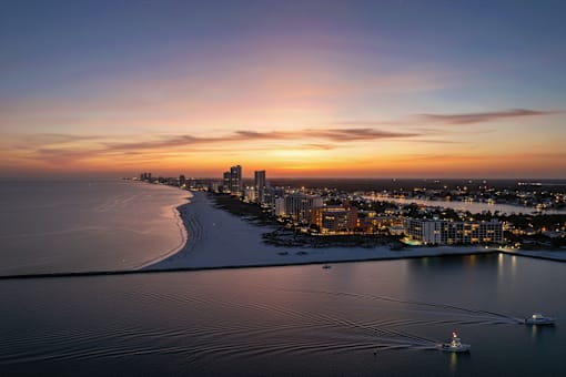 A beautiful sunset over a coastal city with boats in the water.